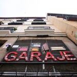 Imagen de la entrada de un garaje privado en Madrid, en el que cuelga la para en rojo "Garaje", y en el que se encuentran numerosos carteles de se vende y se alquila plaza de garaje para coche o moto.