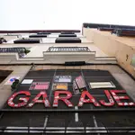 Imagen de la entrada de un garaje privado en Madrid, en el que cuelga la para en rojo &quot;Garaje&quot;, y en el que se encuentran numerosos carteles de se vende y se alquila plaza de garaje para coche o moto.