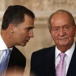 FILE - In this Wednesday June 18, 2014 file photo, Spanish Crown Prince Felipe, left speaks with Spanish King Juan Carlos after he signed an abdication law during a ceremony at the Royal Palace in Madrid, Spain. Former Spanish King Juan Carlos I has paid close to 4.4 million euros ($5.33 million) in a debt with the countryâ€™s tax authorities it was announced Friday, Feb. 26, 2021, his latest attempt to regularize past undeclared income. The former monarch has been living abroad for more than half a year after media revealed fresh allegations of financial misdoings. (AP Photo/Daniel Ochoa de Olza)