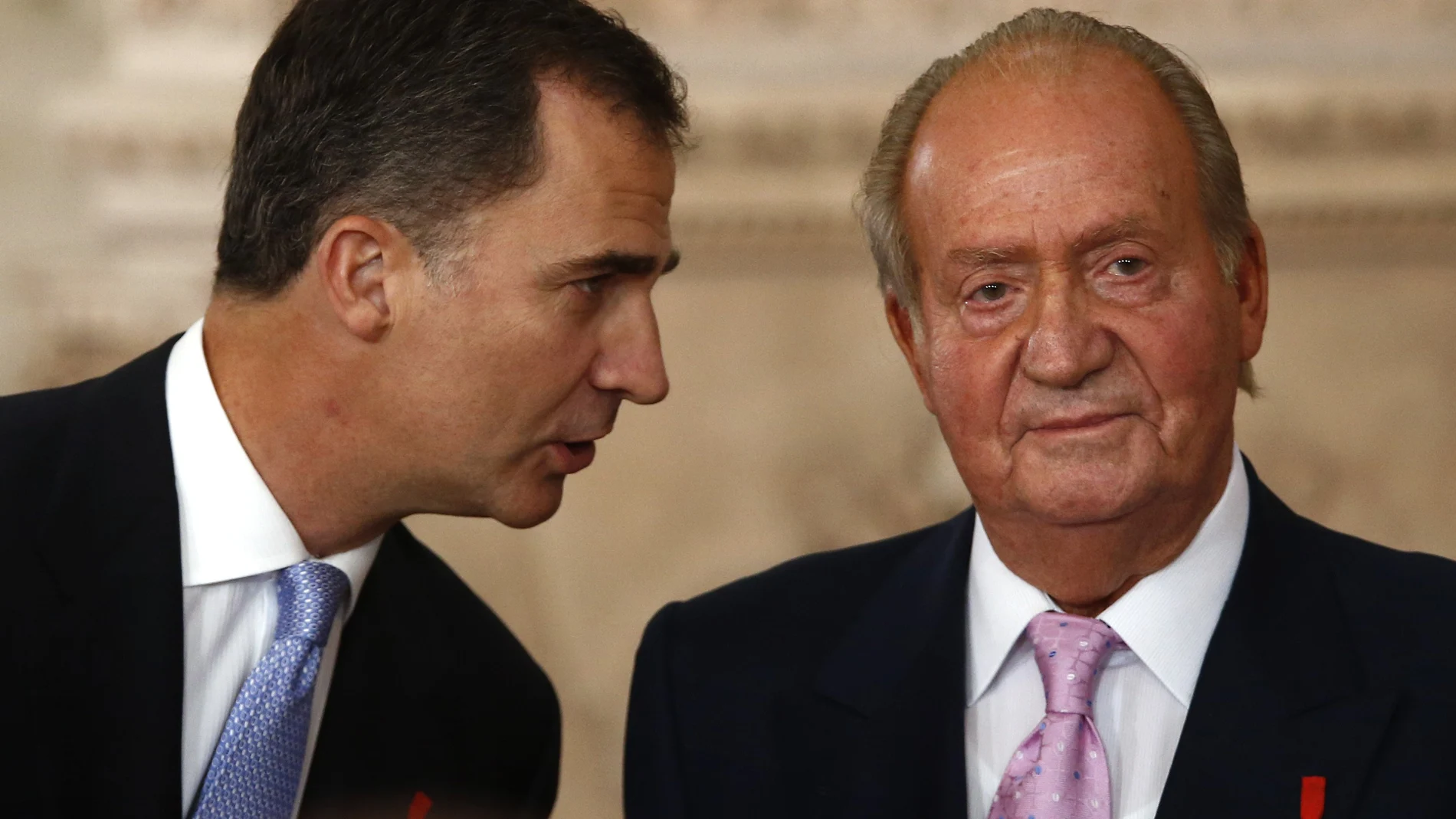 FILE - In this Wednesday June 18, 2014 file photo, Spanish Crown Prince Felipe, left speaks with Spanish King Juan Carlos after he signed an abdication law during a ceremony at the Royal Palace in Madrid, Spain. Former Spanish King Juan Carlos I has paid close to 4.4 million euros ($5.33 million) in a debt with the countryâ€™s tax authorities it was announced Friday, Feb. 26, 2021, his latest attempt to regularize past undeclared income. The former monarch has been living abroad for more than half a year after media revealed fresh allegations of financial misdoings. (AP Photo/Daniel Ochoa de Olza)