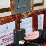 Una persona se pone agua bendita en una de los dispensadores automáticos de agua bendita instalados para reducir al mínimo el riesgo de contagio por COVID 19 o por cualquier otro virus