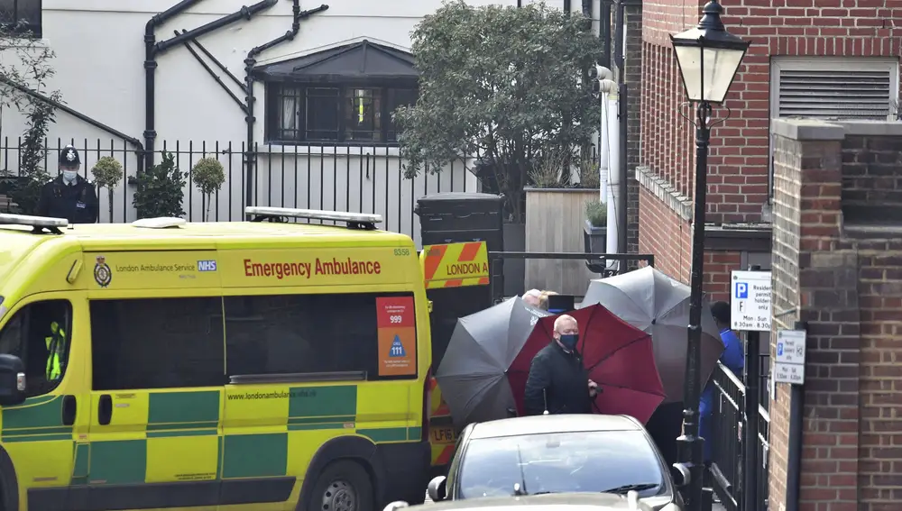El personal usa paraguas para proteger la entrada a una ambulancia en el Hospital King Edward VII en Londres