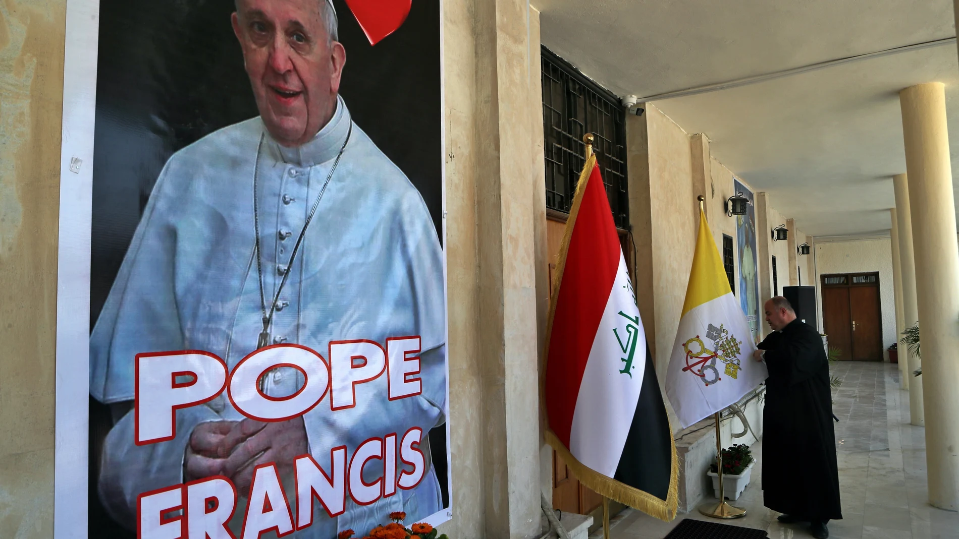 El padre Nazeer Dako arregla una bandera del Vaticano para recibir al Papa Francisco en la Iglesia Caldea de San José antes de la visita del Papa, en Bagdad