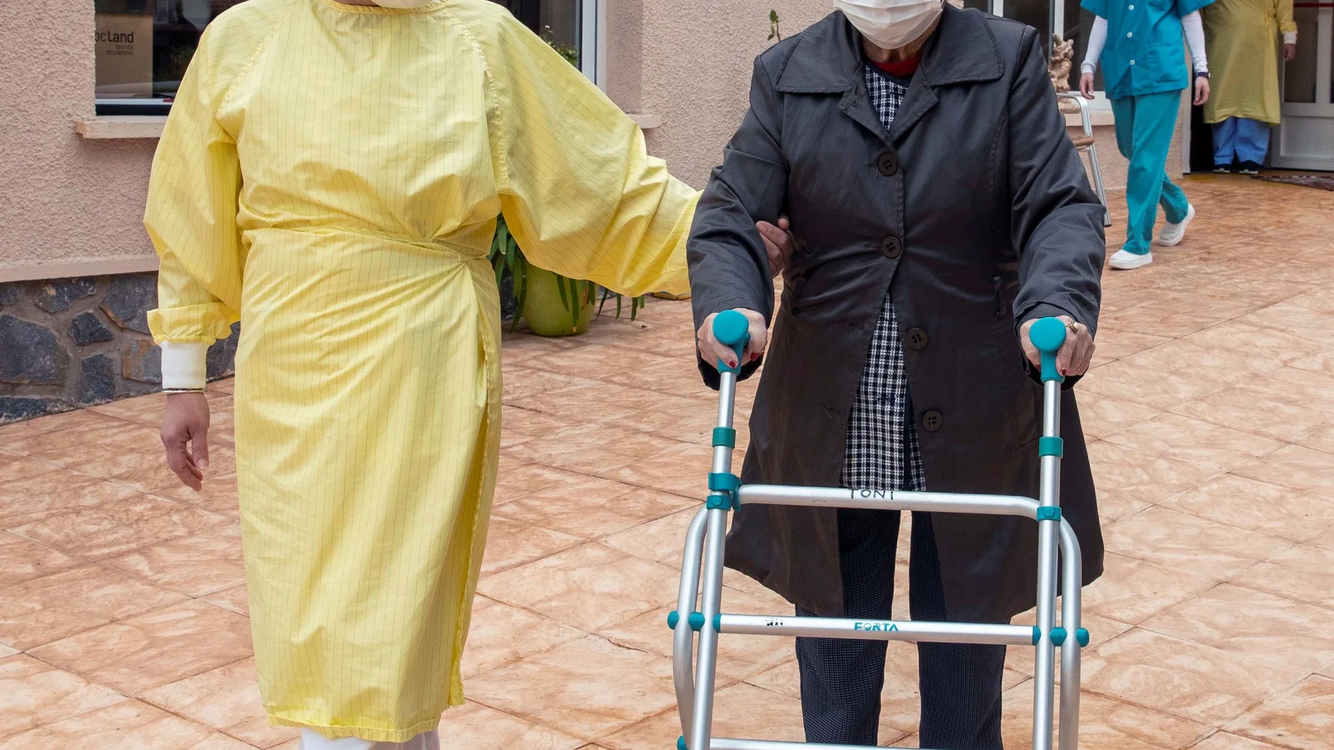 SAN PEDRO DEL PINATAR 02/03/2021.- Una ciudadora ayuda a salir al jardín a una mujer residente en la residencia de personas mayores de Mensajeros de la Paz de San Pedro del Pinatar este martes