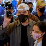 FILE PHOTO: El Salvador's President Nayib Bukele, accompanied by his wife Gabriela de Bukele, shows his finger after casting his vote during the municipal and parliamentary elections in San Salvador, El Salvador, February 28, 2021. REUTERS/Jose Cabezas/File Photo