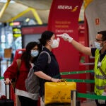 Un funcionario del aeropuerto tomando la temperatura a los pasajeros en un contriol rutinario