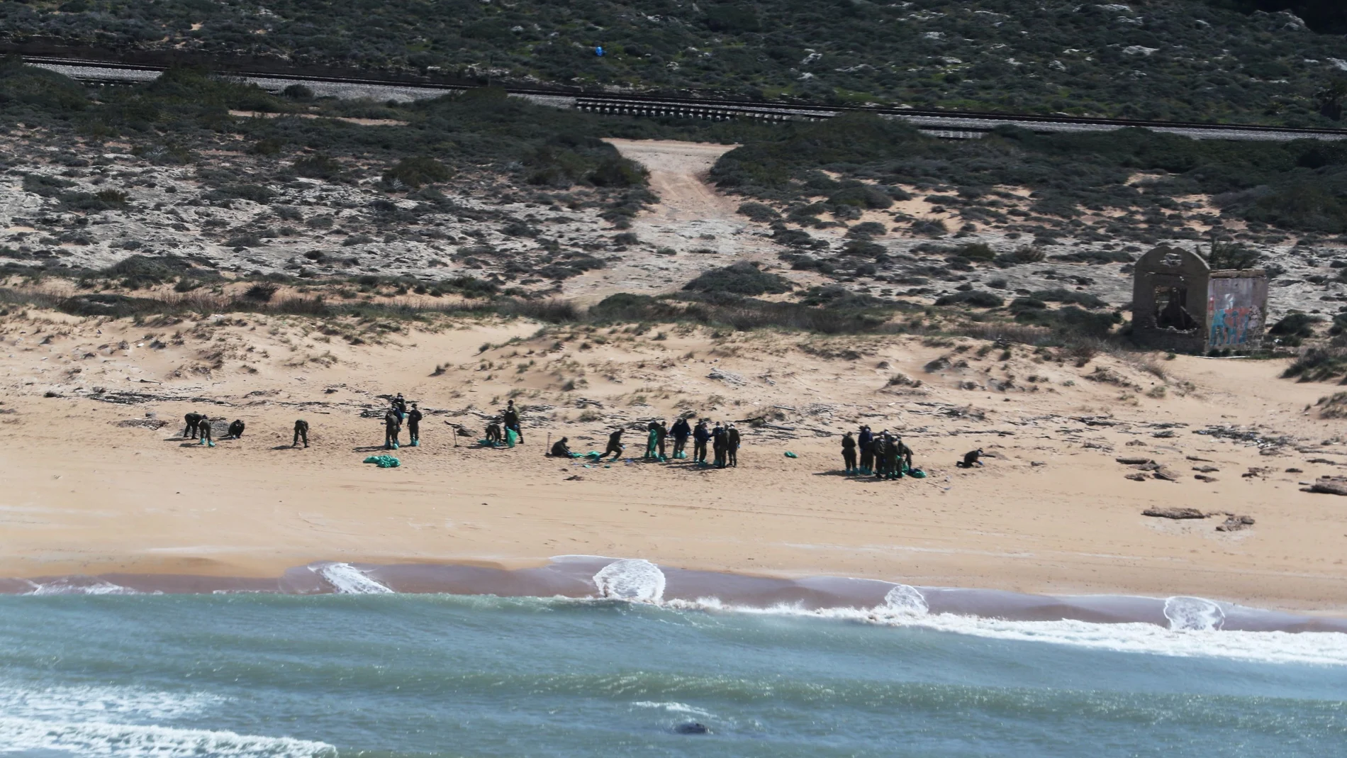 Soldados israelíes con trajes protectores limpian el alquitrán de una playa después de un derrame de petróleo en el Mediterráneo