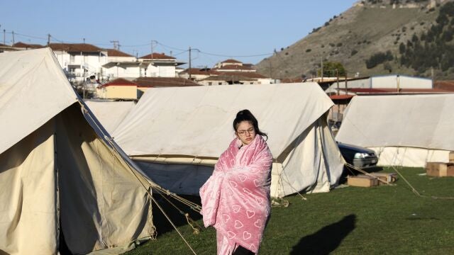 Una niña junto a una tienda de campaña usa una manta para mantenerse abrigada después de un terremoto en la aldea de Damasi, en el centro de Grecia