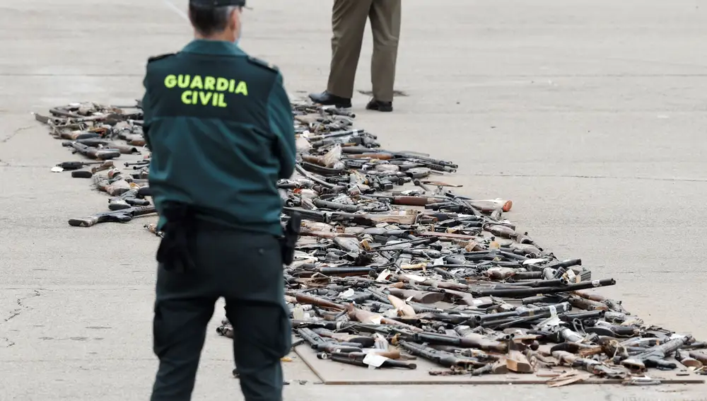 Un Guardia Civil observa la hilera de armas incautadas en décadas pasadas a las bandas terroristas ETA y GRAPO antes de ser destruidas de manera simbólica