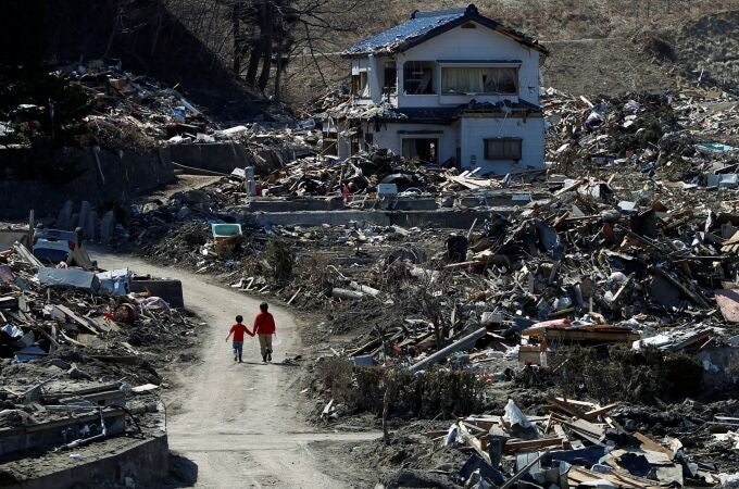 Dos personas pasean por un área devastada el 11 de marzo de 2011 por el terremoto y el posterior tsunami en la prefectura japonesa de Fukushima
