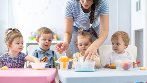 Grupo de bebés de la guardería que comen alimentos saludables a la hora del almuerzo junto con el jardín de infancia
