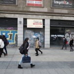 Los peatones transitan por la madrileña Gran Vía ante los locales comerciales cerrados por la crisis económica