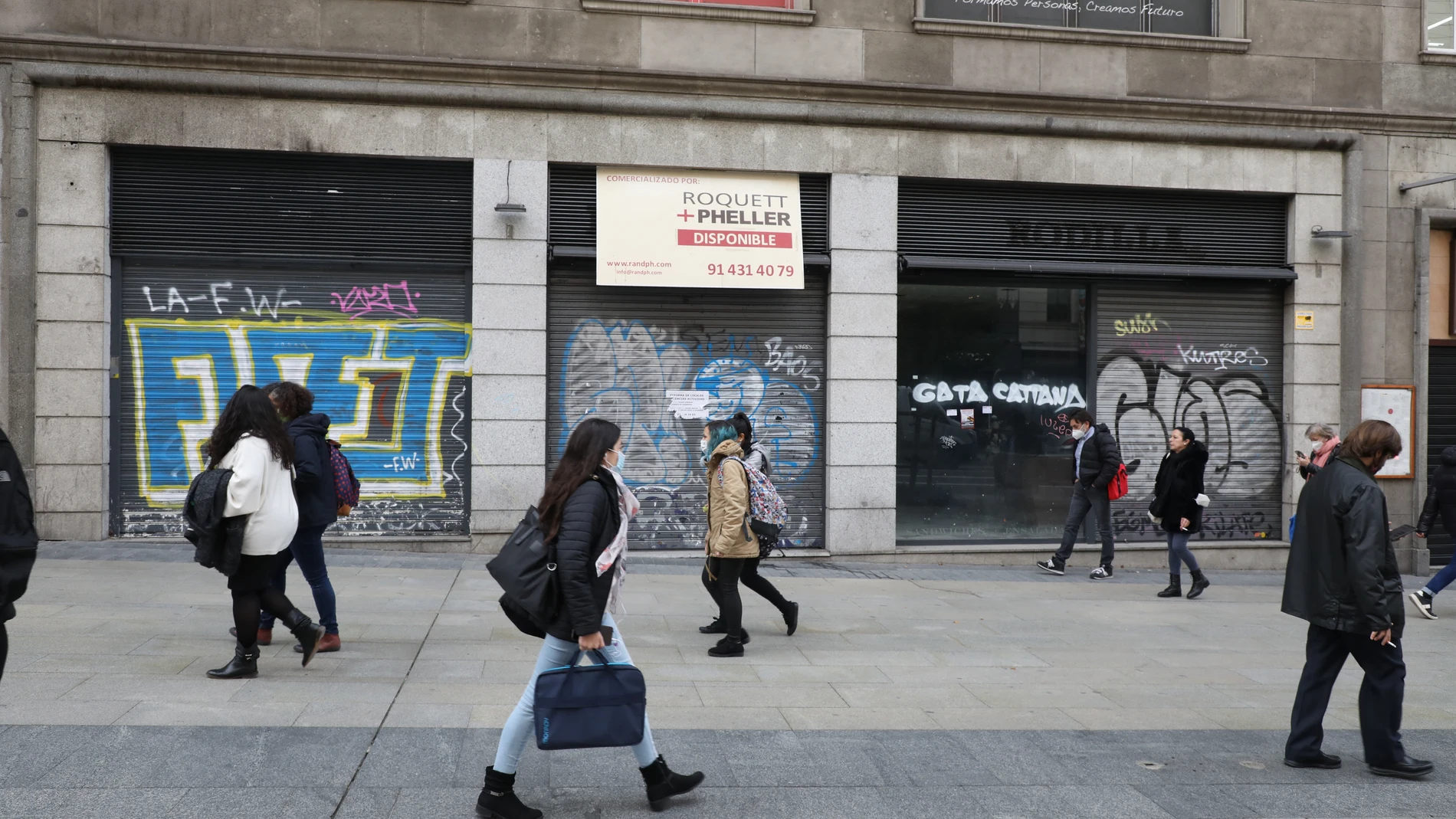 Los peatones transitan por la madrileña Gran Vía ante los locales comerciales cerrados por la crisis económica
