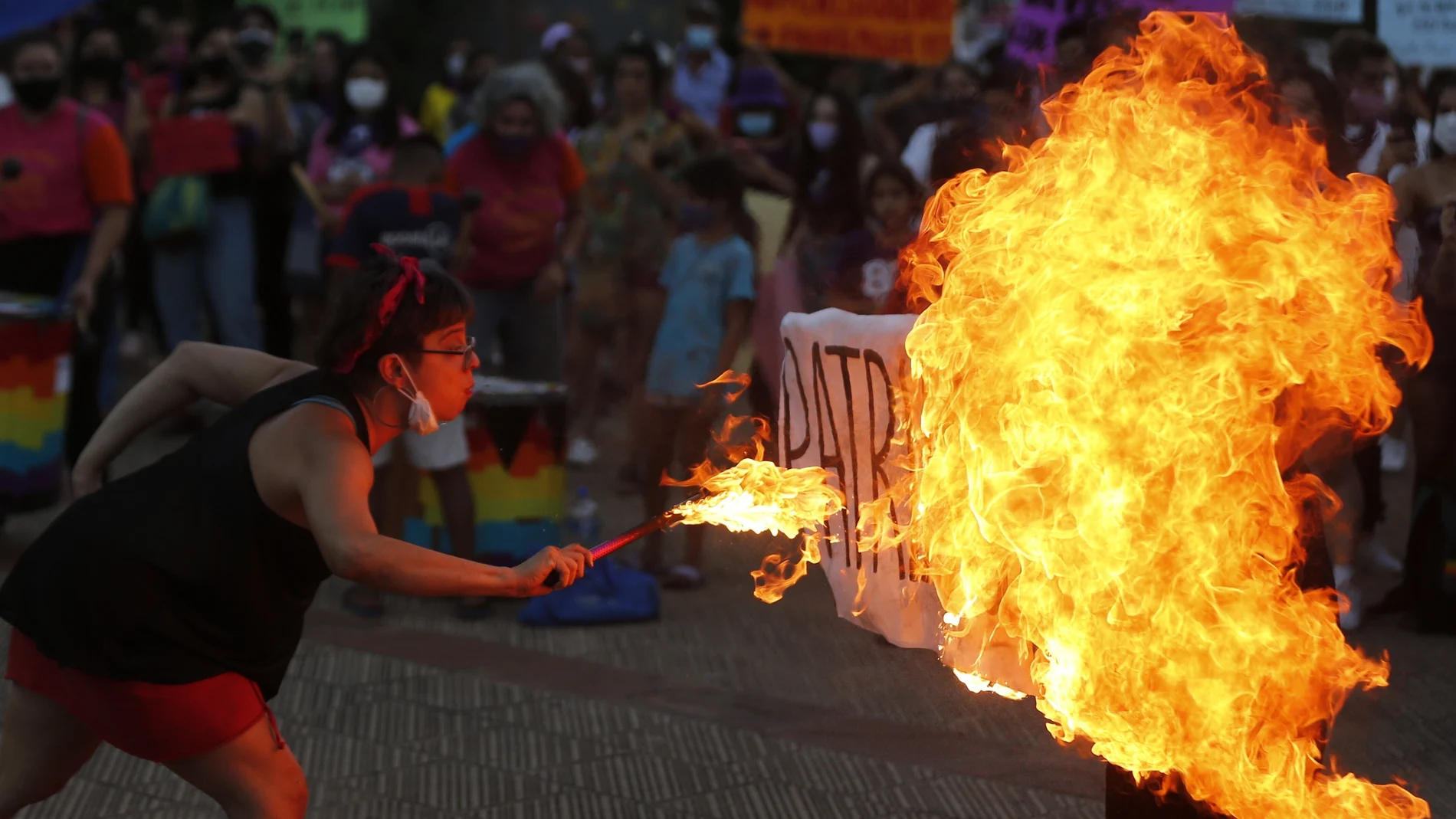 A fire breather burns a poster with the word "Patriarchy" during a march commemorating Women's International Day in Asuncion, Paraguay, Monday, March 8, 2021. (AP Photo/Jorge Saenz)