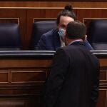 Pablo Iglesias, sentado en el hemiciclo conversa con el ministro de Transportes, José Luis Ábalos