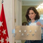 La presidenta de la Comunidad de Madrid, Isabel Díaz Ayuso, se dispone a colocarse la mascarilla al término de una rueda de prensa en la sede regional