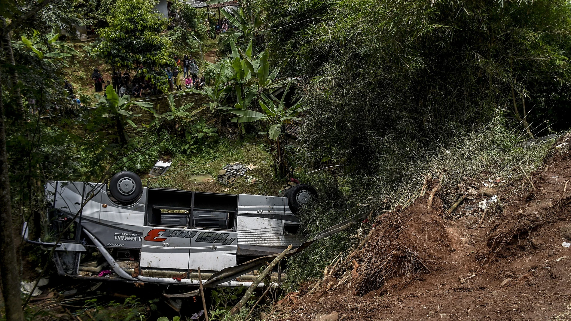 Los residentes inspeccionan los restos de un autobús que se cayó por un barranco en Java Occidental