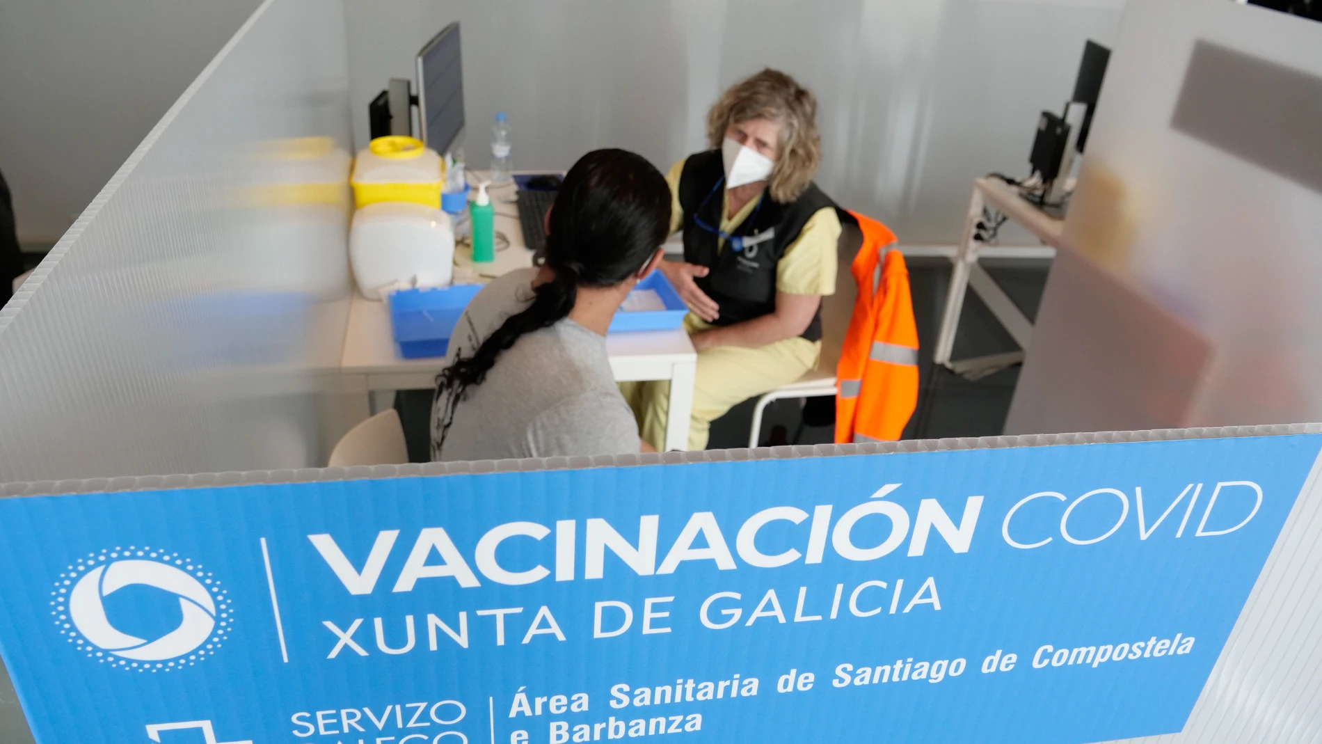 Una mujer habla con una sanitaria en un dispositivo de vacunación contra la COVID-19 en la Cidade da Cultura de Santiago de Compostela, La Coruña