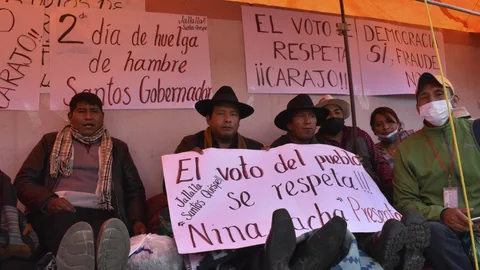 AME2746. LA PAZ (BOLIVIA), 14/03/2021.- El candidato por la Gobernación de La Paz por Jallalla, Santos Quispe (centro), mantiene una huelga de hambre esperando los resultados oficiales afuera del lugar del conteo de votos del departamento hoy, en La Paz (Bolivia). Momentos de tensión se viven a las afueras del centro de cómputo de los votos de las elecciones subnacionales del pasado 7 de marzo en Bolivia, cuando este domingo se cumple el plazo que establece la ley para que se publiquen los resultados oficiales. EFE/ Stringer