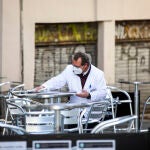 Un camarero limpia las mesas de una terraza con la mascarilla puesta en el centro de Madrid