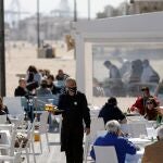 Un camarero atiende las mesas de una terraza en uno de los restaurantes de la playa de la playa de la Malvarrosa de Valéncia