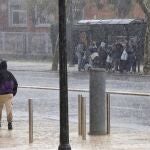 Varias personas se refugian de la fuerte lluvia en una parada de bus