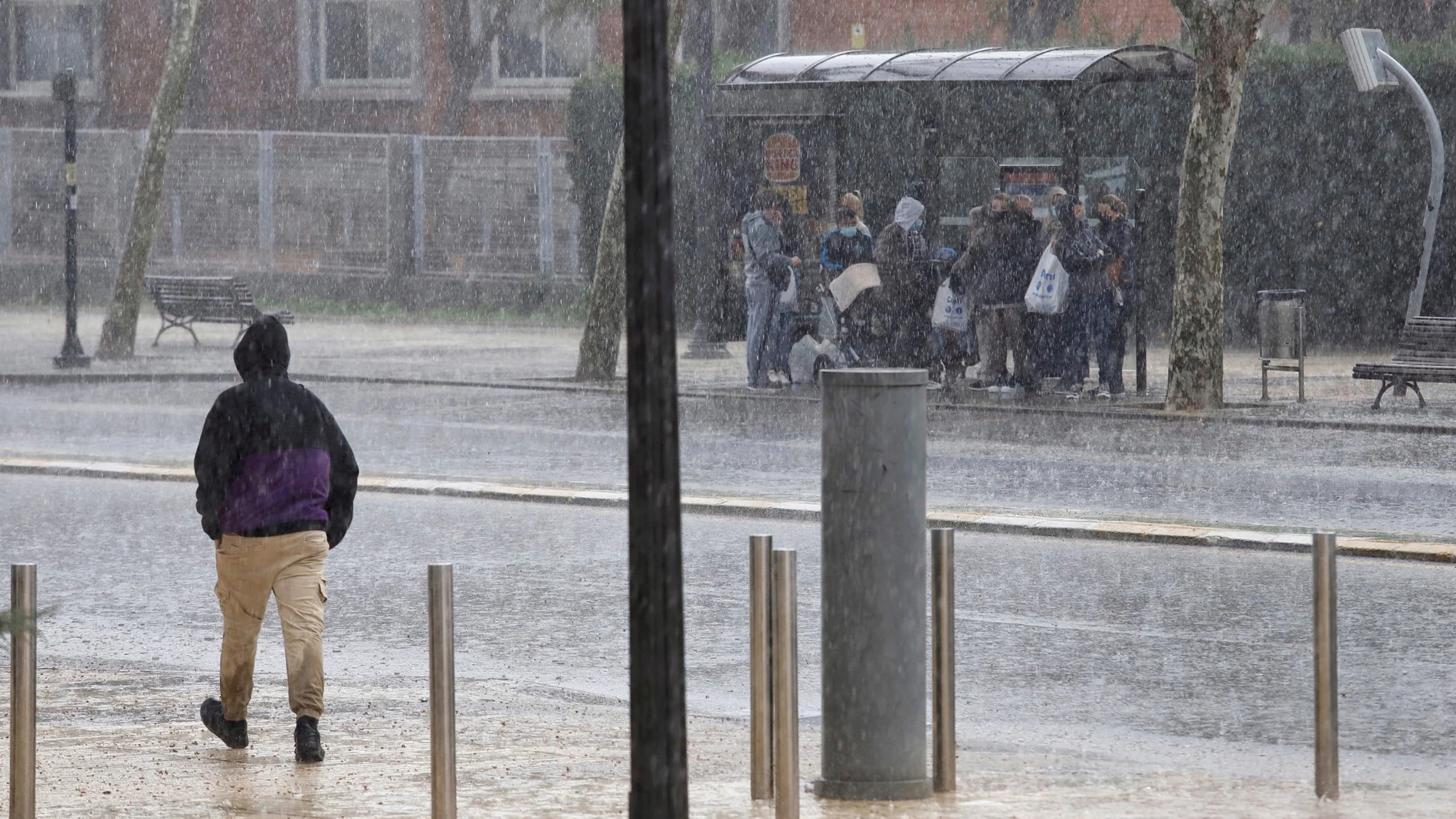 Varias personas se refugian de la fuerte lluvia en una parada de bus