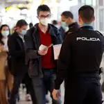 Un policía controla el paso de viajeros en el aeropuerto Adolfo Suárez Madrid-Barajas durante el Día de San José