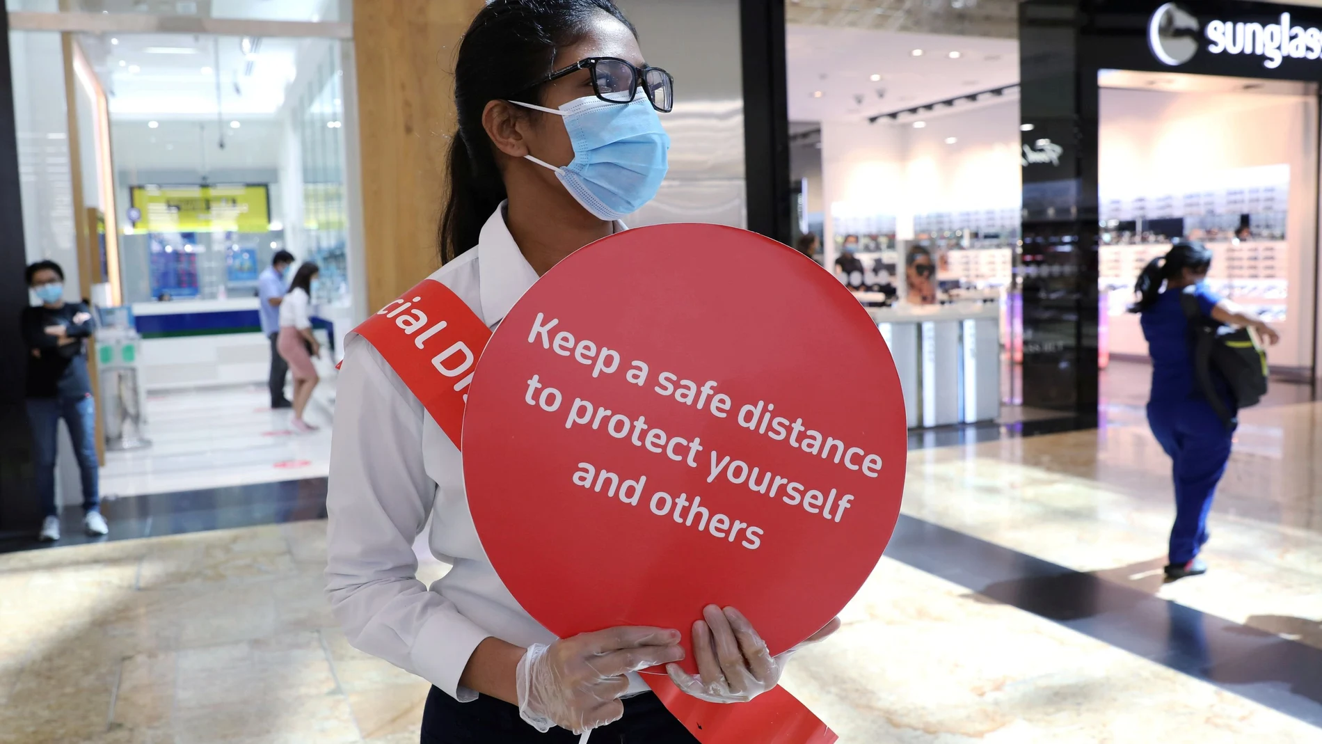 Una mujer con mascarilla recuerda las medidas de seguridad en la reapertura de los centros comerciales en Dubái