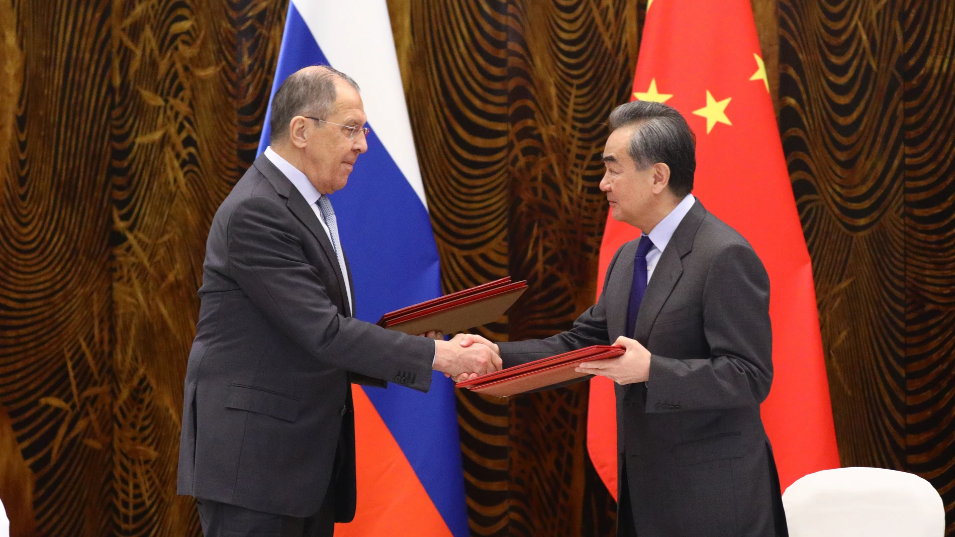 El ministro de Exteriores, Sergei Lavrov, estrecha la mano de su homólogo ruso, Wang Yi, durante su reunión del martes
