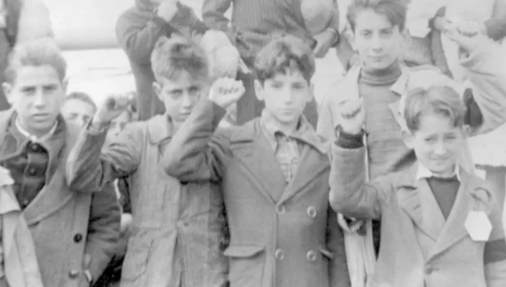 Niños haciendo un saludo comunista antes de ser llevados a la URSS