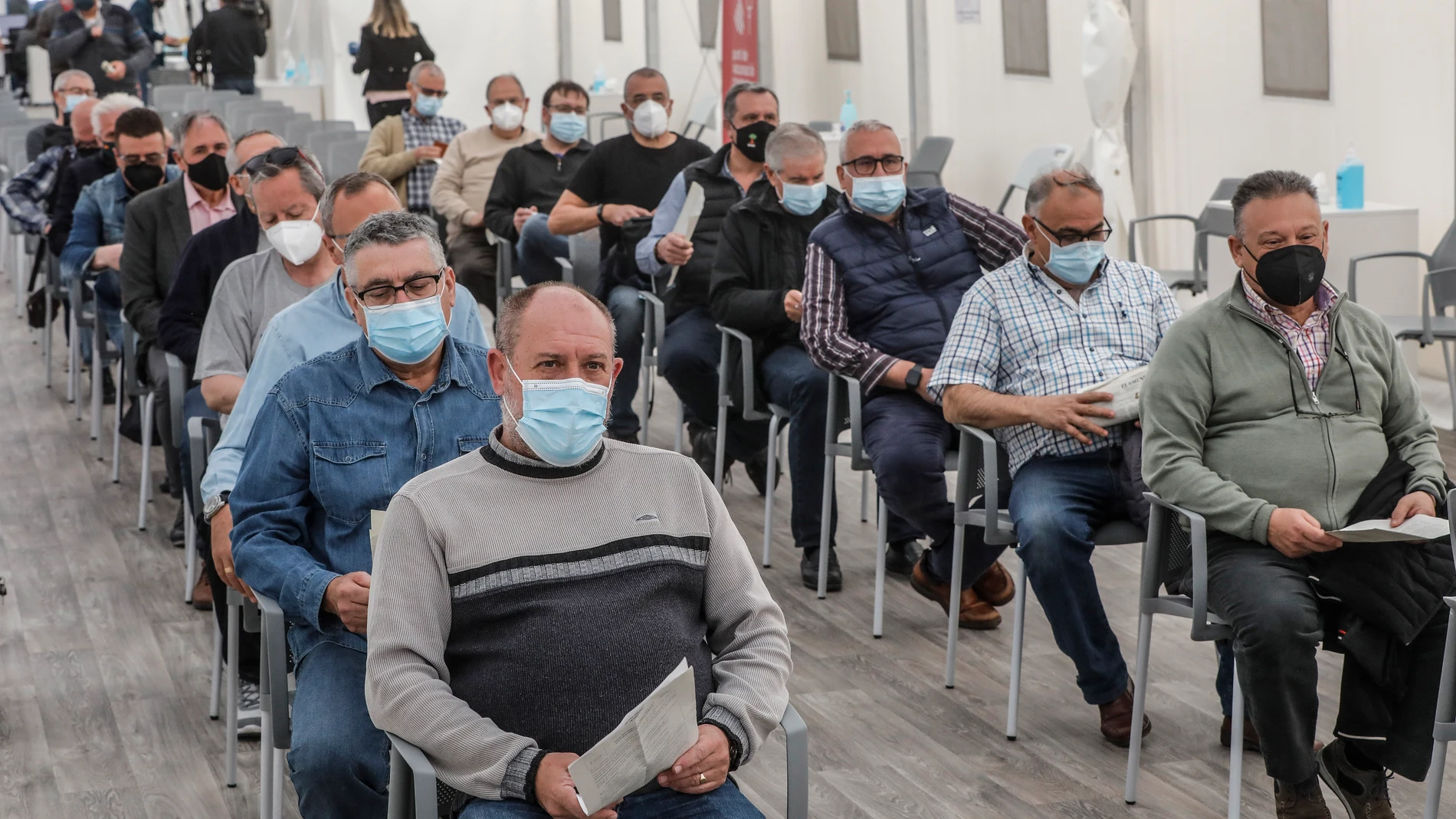 Varios hombres acuden a recibir la primera dosis de la vacuna de AstraZeneca en el Hospital la Fe, en Valencia