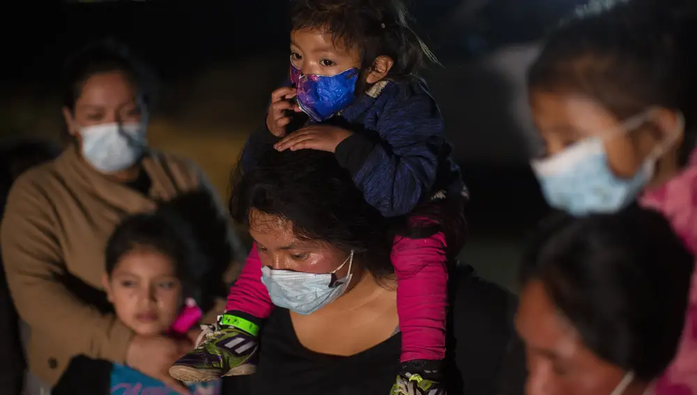 Familias migrantes de Guatemala esperan a una patrulla fronteriza de EE UU después de haber cruzado el Río Grande en una balsa inflable