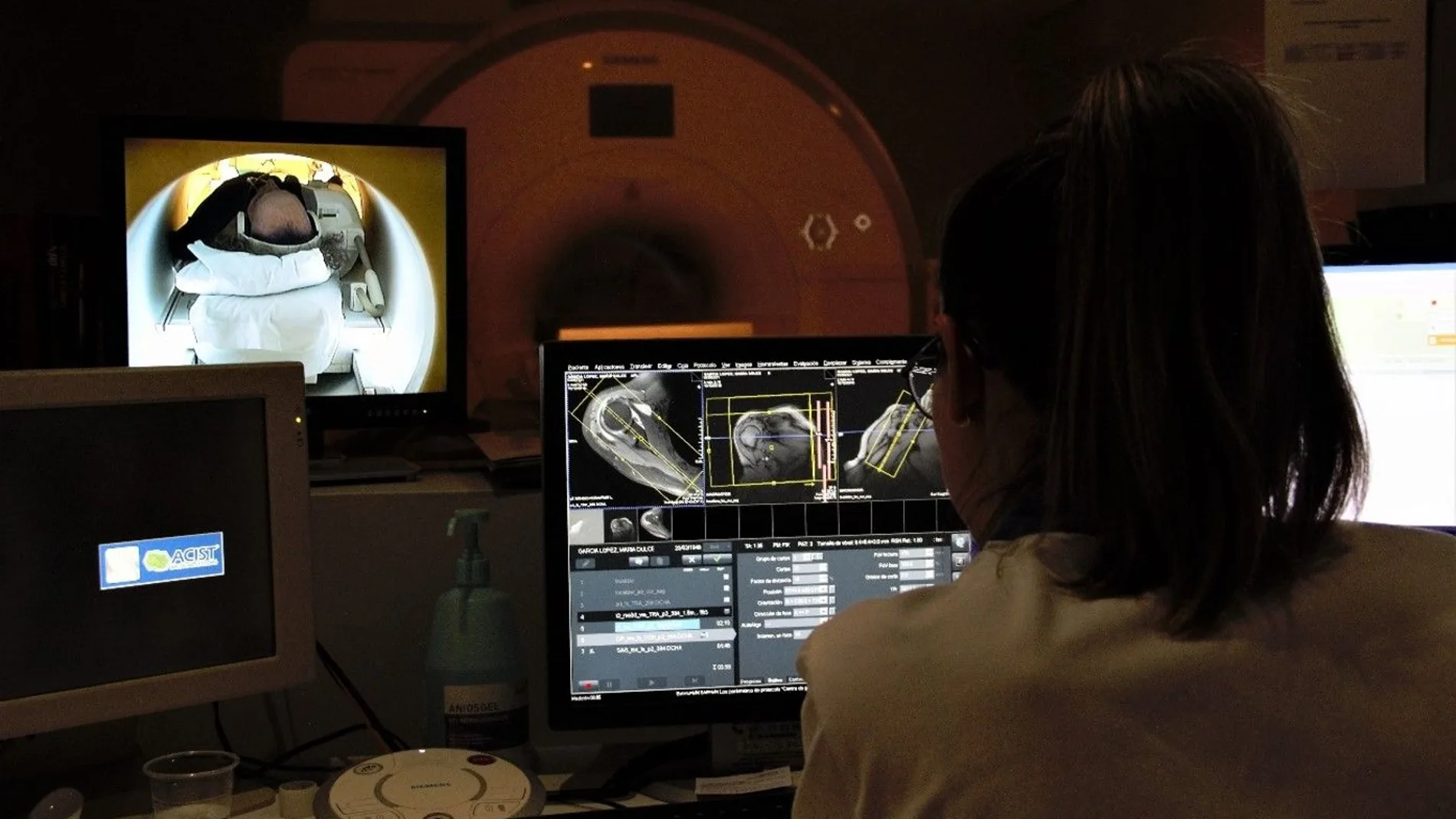 Médica analizando imágenes médicas en un ordenador, en la sala de control de resonancia magnética.