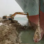 Una excavadora trata de retirar arena de la orilla para desencallar al carguero Ever Given