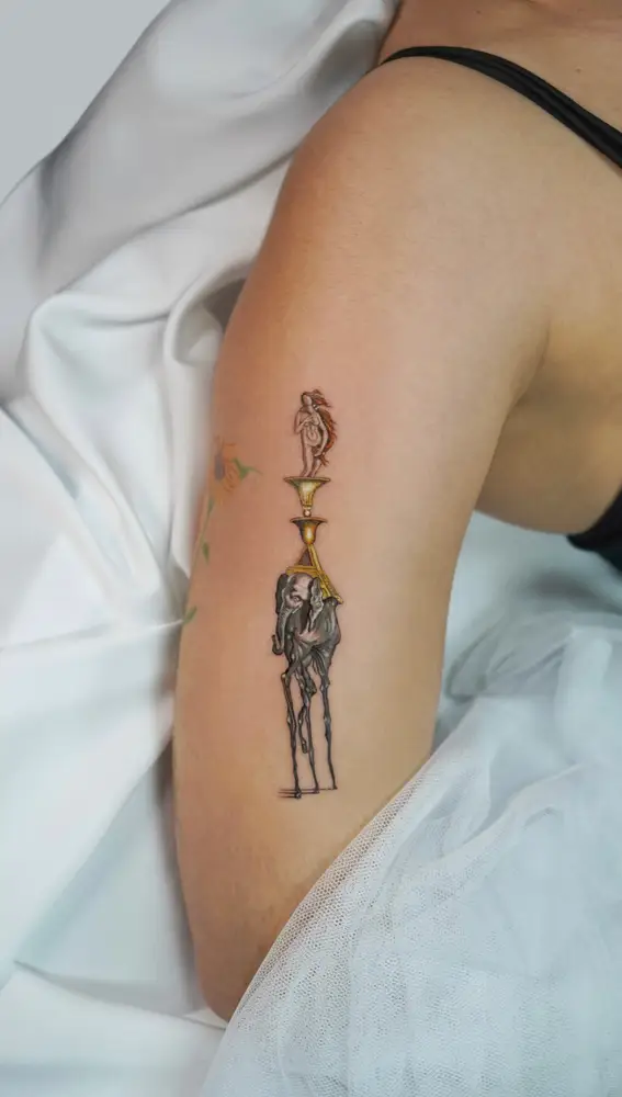 Tatuaje compuesto con escenas de cuadros de Dalí y Botticelli, realizado por Caótida