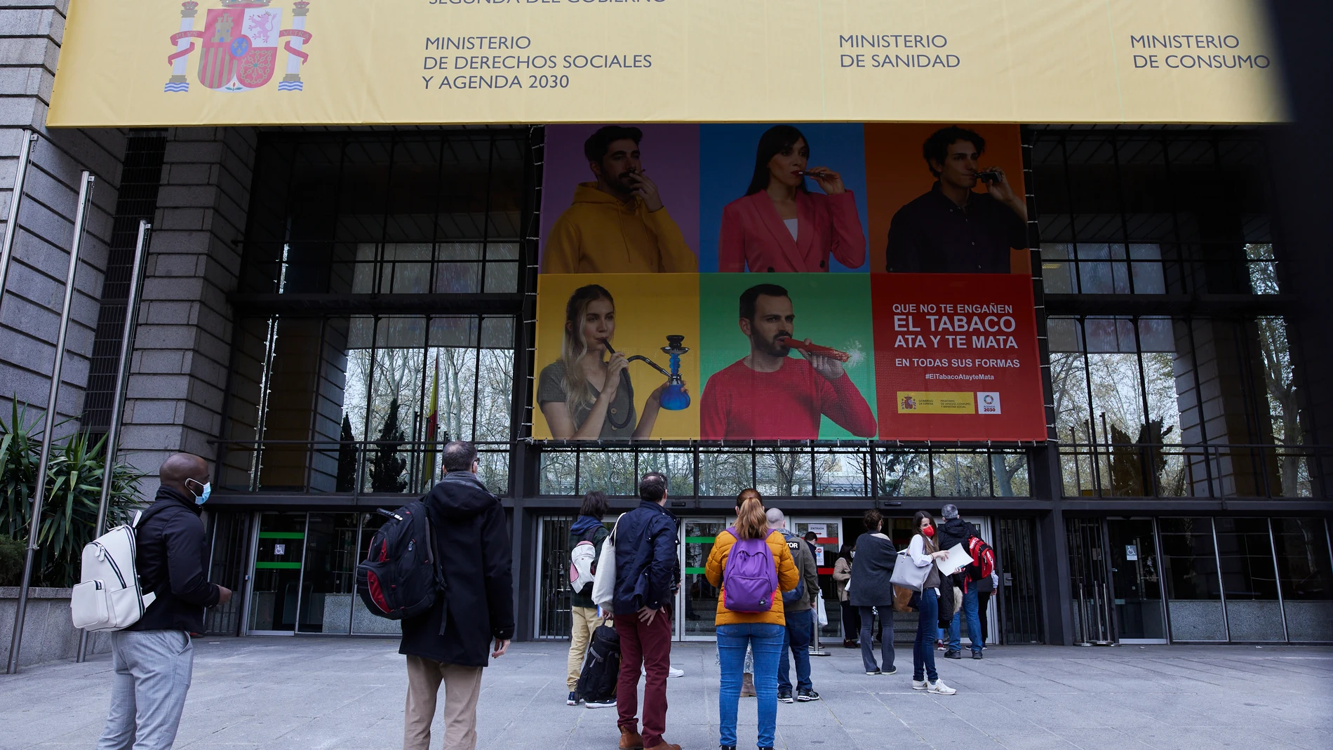 Varias personas hacen cola en el exterior del Ministerio de Sanidad para acceder al centro de examen de las pruebas de Formación Sanitaria Especializada (FSE), en Madrid