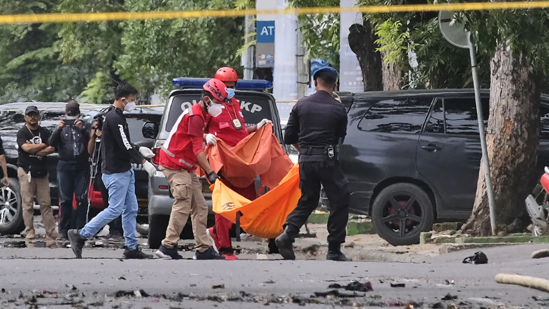 Policías y miembros del equipo de emergencias portan el cadáver de uno de los terroristas a las afueras de la iglesia en Makassar, Indonesia