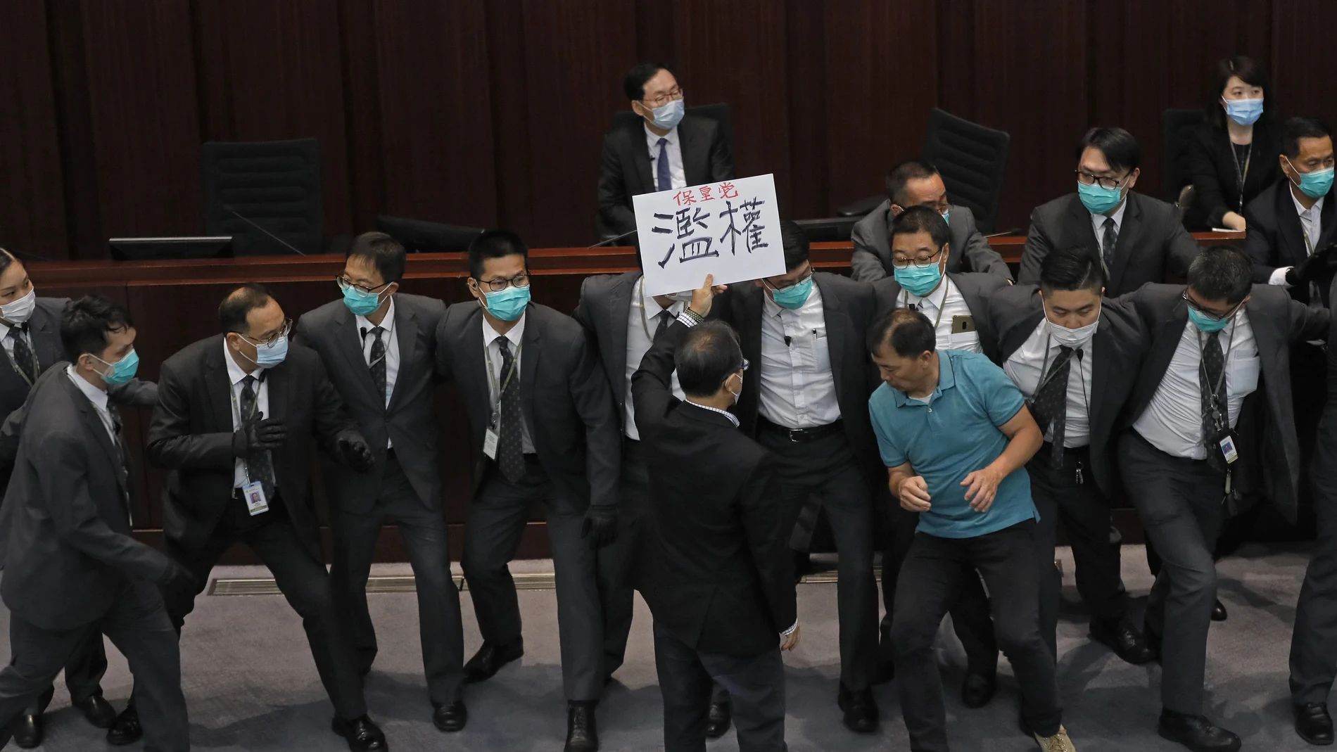 FILE - In this Monday, May 18, 2020, file photo, pro-democracy lawmaker Wu Chi-wai, right in polo shirt, scuffles with security guards during a Legislative Council's House Committee meeting in Hong Kong. China's top legislature approved amendments to Hong Kong's constitution on Tuesday, March 30, 2021, that will give Beijing more control over the make-up of the city's legislature.Â  (AP Photo/Vincent Yu, File)