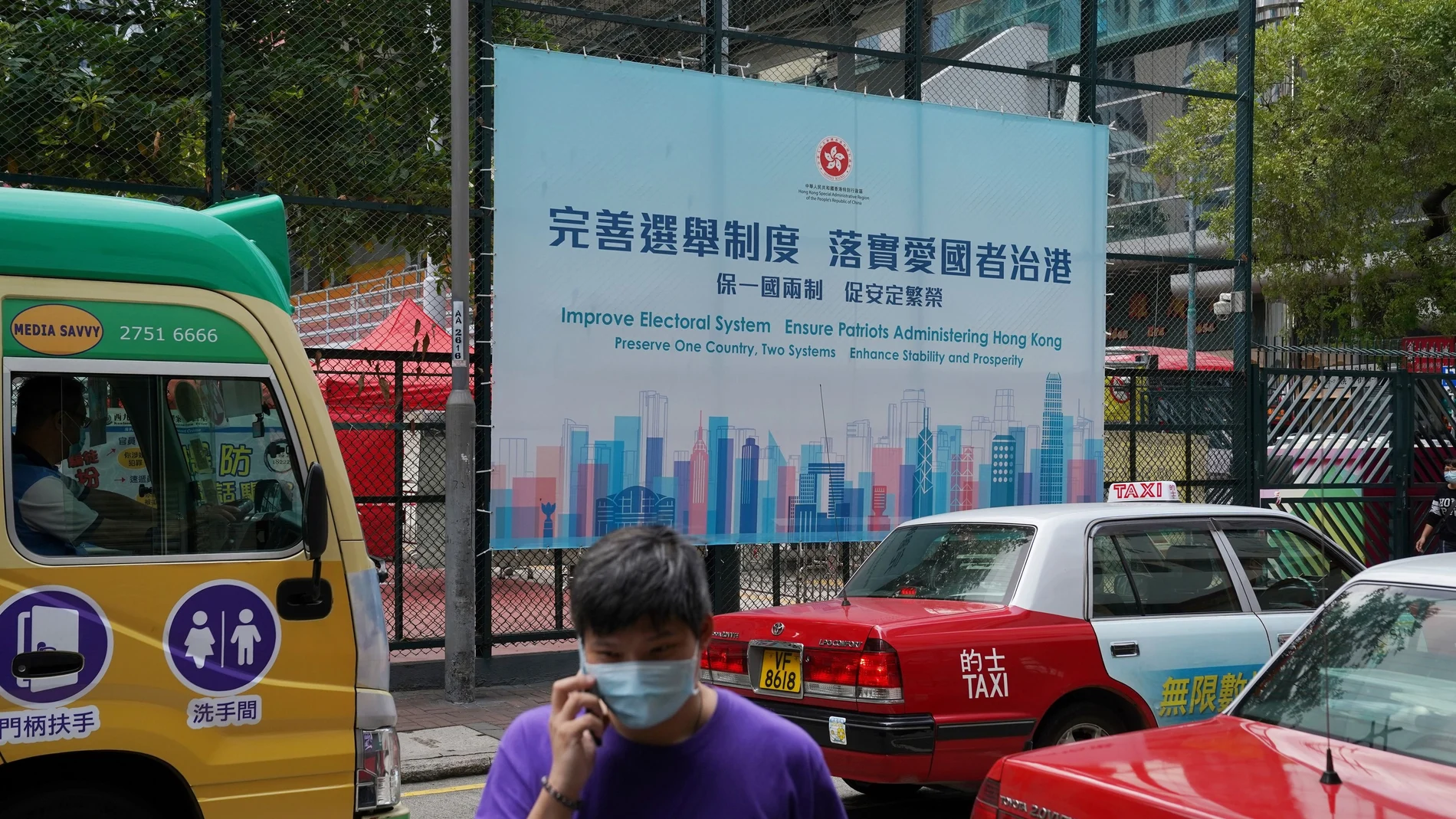 Un hombre pasa junto a un anuncio del gobierno que promueve las reformas electorales de Hong Kong