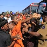 FILE - In this Jan. 7, 2017, file photo, a Sri Lankan Buddhist monk and villagers argue with police officers during a protest outside the inauguration ceremony of an industrial zone in which China had a major stake in Mirijjawila village in Ambalantota, Sri Lanka. China's loans to poor countries in Africa and Asia impose unusual secrecy and repayment terms that are hurting their ability to renegotiate debts after the coronavirus pandemic, a group of U.S. and German researchers said in a report Wednesday, March 31, 2021. (AP Photo/Eranga Jayawardena, File)