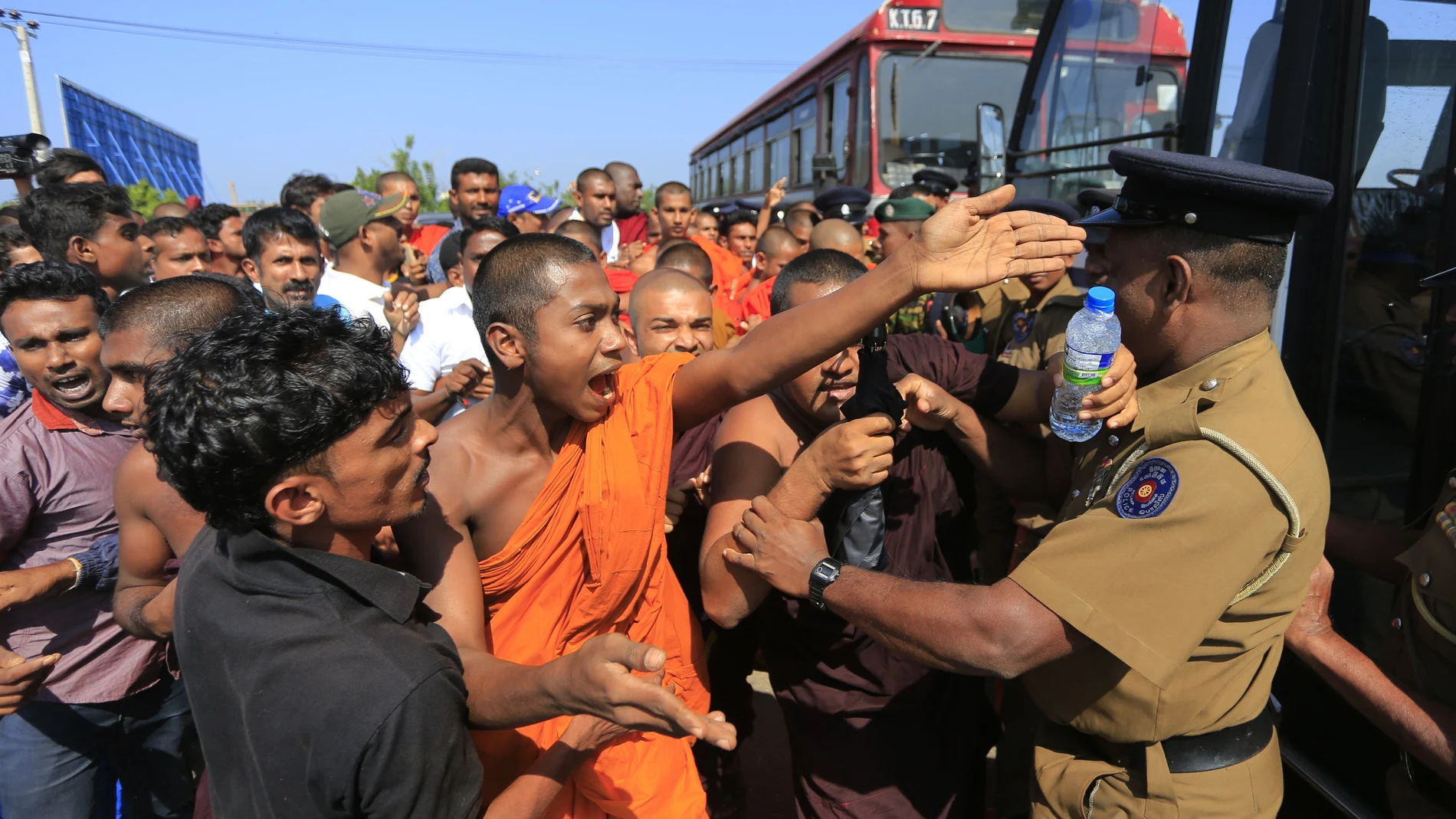 FILE - In this Jan. 7, 2017, file photo, a Sri Lankan Buddhist monk and villagers argue with police officers during a protest outside the inauguration ceremony of an industrial zone in which China had a major stake in Mirijjawila village in Ambalantota, Sri Lanka. China's loans to poor countries in Africa and Asia impose unusual secrecy and repayment terms that are hurting their ability to renegotiate debts after the coronavirus pandemic, a group of U.S. and German researchers said in a report Wednesday, March 31, 2021. (AP Photo/Eranga Jayawardena, File)