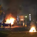 Un hombre pasa junto a un coche incendiado en Belfast la noche del sábado