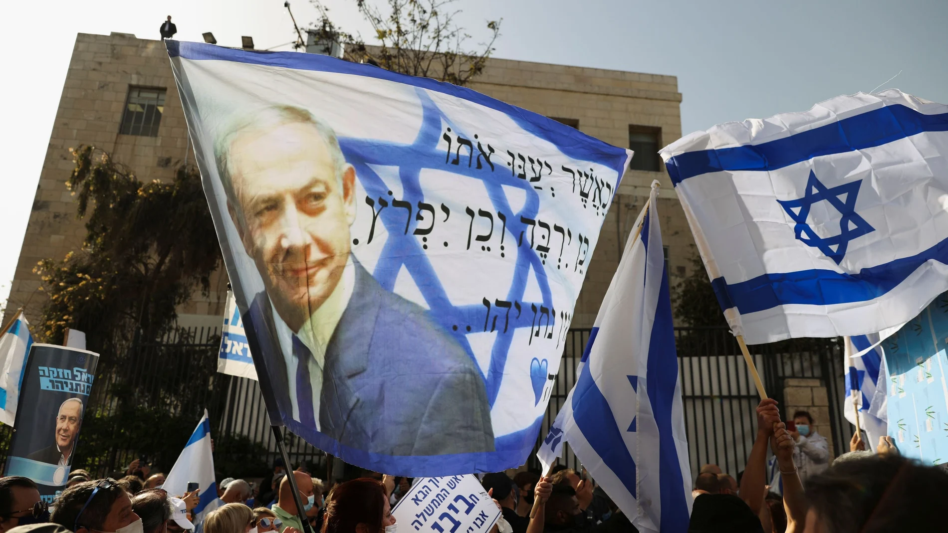 Partidarios del primer ministro israelí ondean una bandera israelí con una imagen de Netanyahu, mientras se reanuda su juicio por corrupción, cerca del Tribunal de Distrito de Jerusalén