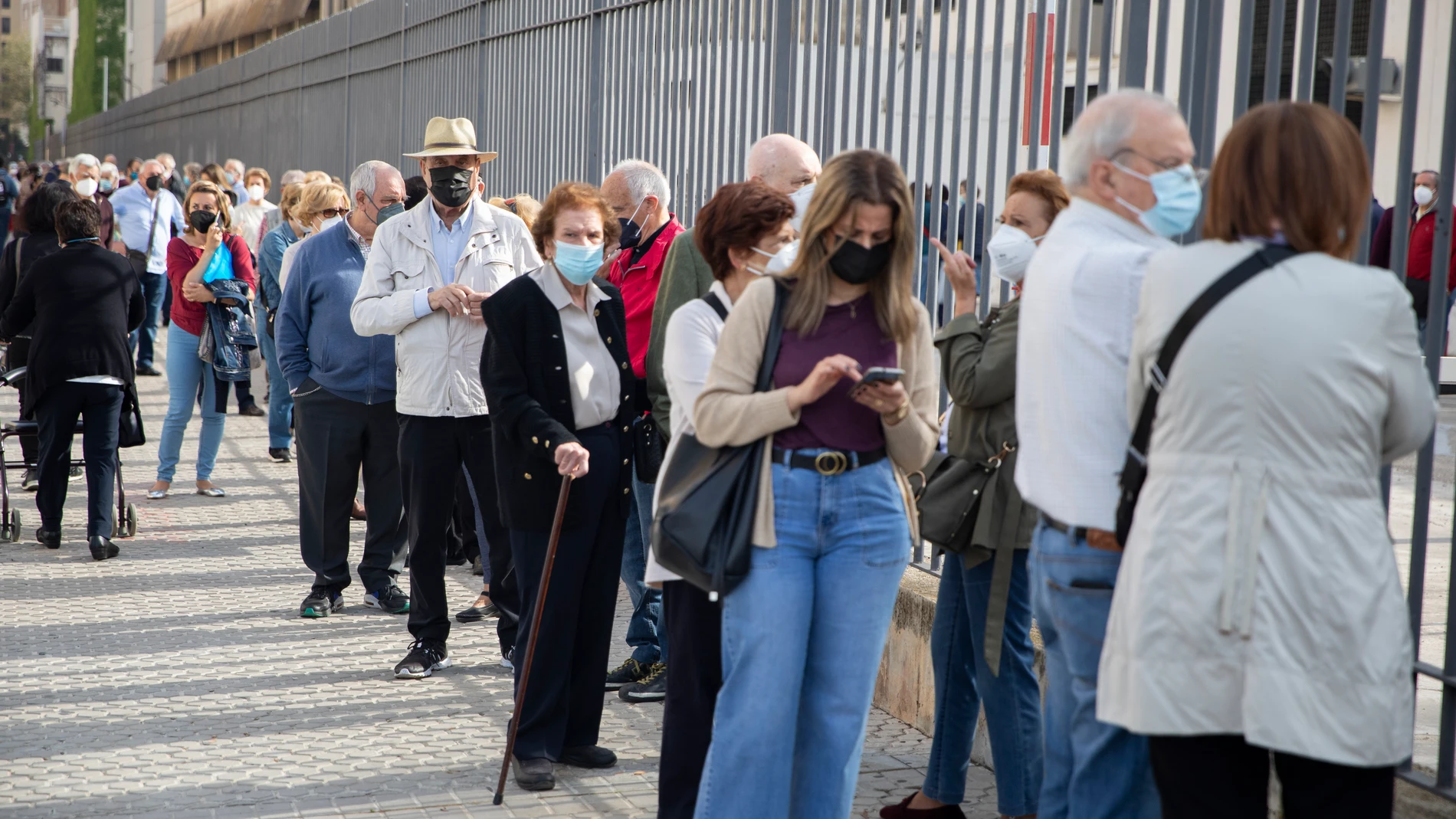 Personas mayores hacen cola en Sevilla esperando su turno de vacunación