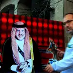 Un hombre pasa junto a un cartel del rey Abdulá