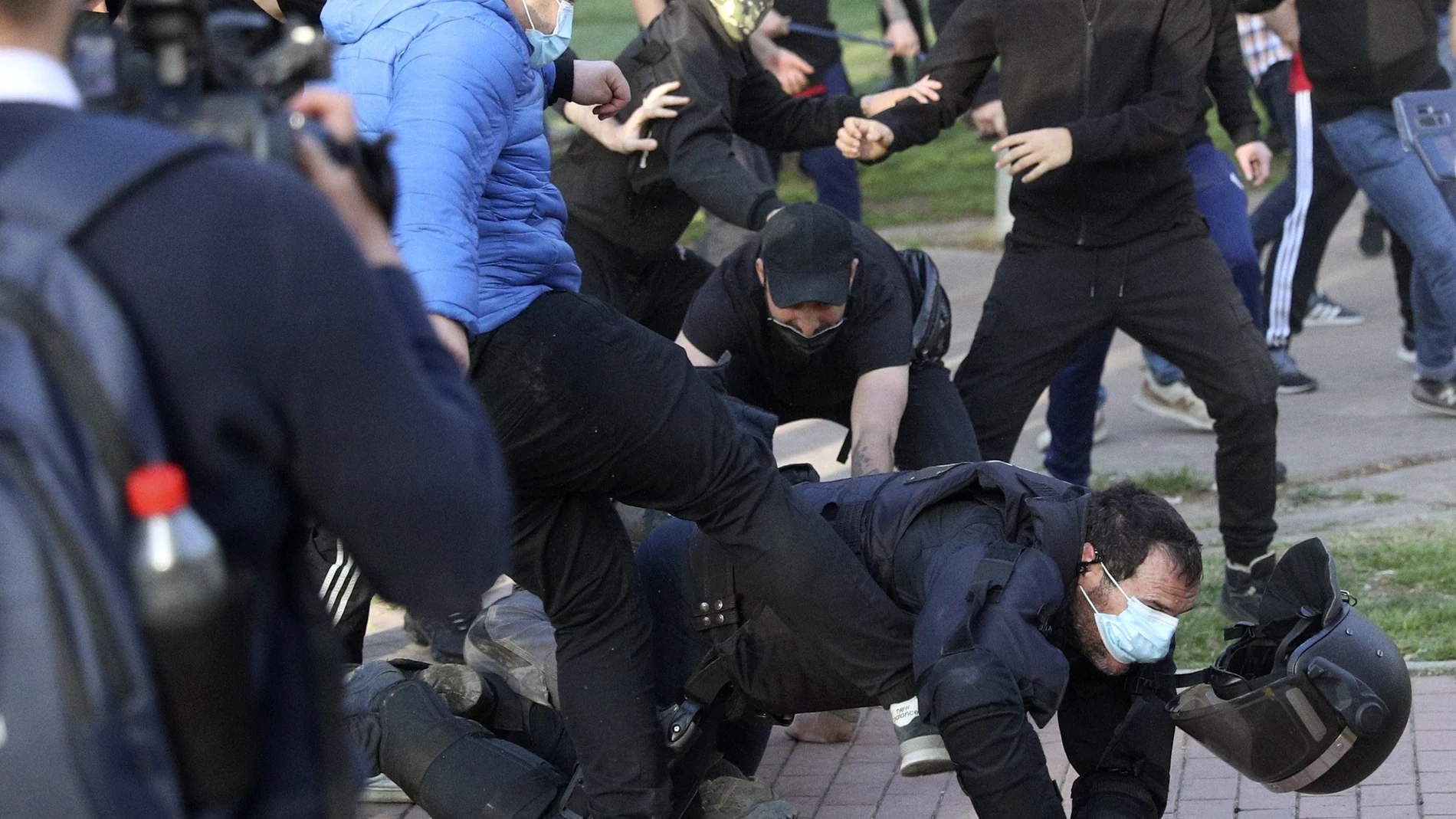Radicales patean a un policía en el suelo y sin casco durante el mitin de Vox en la Plaza Roja de Vallecas, el miércoles z