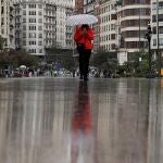 Una persona se protege con un paraguas de la lluvias en la plaza del Ayuntamiento