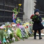Una niña deja flores en la verga del Palacio de Buckhingham en recuerdo del príncipe Felipe