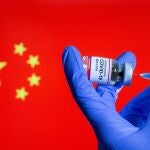 FILE PHOTO: FILE PHOTO: A woman holds a small bottle labeled with a "Coronavirus COVID-19 Vaccine" sticker and a medical syringe in front of displayed China flag in this illustration taken, October 30, 2020. REUTERS/Dado Ruvic/File Photo/File Photo